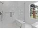 Bathroom with a frameless glass shower, white marble tile, and black fixtures at 1349 Oak Road, Lilburn, GA 30047