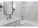 Bathroom featuring a marble tiled bathtub and shower, a modern vanity, and black fixtures at 1349 Oak Road, Lilburn, GA 30047