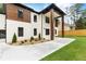 Striking two-story home with a modern design, showcasing white brick, wood accents, and manicured landscaping at 1349 Oak Road, Lilburn, GA 30047