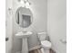This bathroom has a pedestal sink, a round mirror, and wood-look flooring at 1462 Stephens View Dr, Loganville, GA 30052