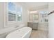 Bright bathroom featuring a soaking tub, a vanity with modern fixtures, and shuttered windows at 5981 Brundage Ln, Norcross, GA 30071