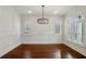 Bright, spacious living room featuring beautiful hardwood floors, white trim, plantation shutters, and a stylish chandelier at 5981 Brundage Ln, Norcross, GA 30071