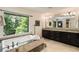 Luxurious bathroom with tub, walk-in shower, double vanity, and view of lush greenery at 1053 Crane Ne Rd, Atlanta, GA 30324
