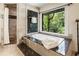 Bright bathroom with tub, walk-in shower, marble tile, and a view of lush greenery at 1053 Crane Ne Rd, Atlanta, GA 30324