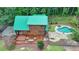 Aerial view of a log cabin with a green roof, deck, and swimming pool surrounded by lush greenery at 2864 Winder Hwy, Dacula, GA 30019