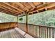 View of a covered deck with wooden floors, beams and railings overlooking a lush wooded area at 2864 Winder Hwy, Dacula, GA 30019