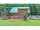 A log cabin with a green roof and a spacious wooden deck with outdoor furniture at 2864 Winder Hwy, Dacula, GA 30019