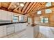 Bright kitchen with white cabinets, black countertops, and a wooden ceiling adjacent to a large living space at 2864 Winder Hwy, Dacula, GA 30019