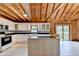 Spacious kitchen features wooden ceiling, white cabinets, black countertops and an island in the middle at 2864 Winder Hwy, Dacula, GA 30019