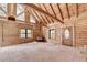 Log cabin interior featuring a carpeted living room with wood walls, high ceilings, and a wood burning stove at 2864 Winder Hwy, Dacula, GA 30019