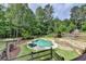 A backyard with a kidney-shaped pool surrounded by greenery and a wooden fence at 2864 Winder Hwy, Dacula, GA 30019