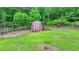 View of a shed with a wooden door and a red frame sitting on a well-manicured lawn at 2864 Winder Hwy, Dacula, GA 30019