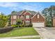 Inviting brick home with a two-car garage, lush lawn, and manicured landscaping at 4045 Bonnett Creek Ln, Hoschton, GA 30548