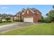 Beautiful red brick home featuring an attached two-car garage and manicured green lawn at 4045 Bonnett Creek Ln, Hoschton, GA 30548