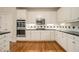 Well-lit kitchen features stainless steel appliances, white cabinetry, black countertops and hardwood floors at 4045 Bonnett Creek Ln, Hoschton, GA 30548