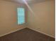 A cozy bedroom featuring neutral-toned walls and carpet, with a window for natural light at 1165 Oaks Pl, Stone Mountain, GA 30083