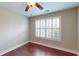 Comfortable bedroom featuring hardwood floors, a ceiling fan, and plantation shutters for natural light at 2058 Bonneville Ln, Powder Springs, GA 30127