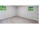 Bright bedroom with laminate flooring and two windows offering exterior views at 5857 Earlwane Dr, Lithonia, GA 30058