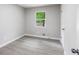 Simple bedroom with light walls and trim, laminate flooring, and a view to mature landscaping at 5857 Earlwane Dr, Lithonia, GA 30058