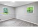 Bright and airy bedroom featuring two windows and laminate flooring at 5857 Earlwane Dr, Lithonia, GA 30058