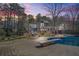 Twilight view of the home's backyard, featuring a pool and lounging areas with the lights on at 65 Deer Run Ln, Mcdonough, GA 30252