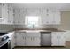 This kitchen offers white cabinets, granite countertops, a stainless steel dishwasher, and a farmhouse sink at 87 Virgil Sw St, Mableton, GA 30126