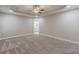 Spacious bedroom with neutral carpet, tray ceiling, ceiling fan, and access to bathroom at 150 Whitworth Dr, Locust Grove, GA 30248
