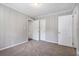 Cozy bedroom with wood paneled walls, plush carpet, closet, and a doorway leading to another room at 1879 Rosewood Rd, Decatur, GA 30032