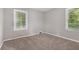Cozy bedroom featuring neutral walls, plush carpeting, and two bright windows with wooded views at 1879 Rosewood Rd, Decatur, GA 30032