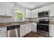 Kitchen with stainless steel appliances, granite countertops, white cabinets, and a bright window at 1879 Rosewood Rd, Decatur, GA 30032
