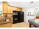 Functional kitchen with wood cabinets, granite countertops, stainless steel microwave, and black appliances, adjacent to a dining area at 228 Olympic Pl # 47, Decatur, GA 30030