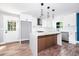View of the remodeled kitchen featuring stainless steel appliances, an island, white cabinets and stylish pendant lighting at 8420 Sheridan Dr, Jonesboro, GA 30236