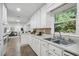 Bright kitchen featuring a double basin sink, white cabinetry, and view to the living room at 2384 Shadowood Sw Dr, Conyers, GA 30094
