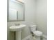 Elegant half bathroom featuring pedestal sink, stylish mirror, and modern toilet at 3018 Old Covington Rd, Covington, GA 30014