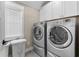 Bright laundry room featuring front-load washer and dryer set with white cabinets and a window at 958 Austin Ne Ave, Atlanta, GA 30307