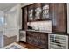 Stylish wet bar with dark wood cabinets, glass display shelving, a sink, and built-in beverage refrigerator at 272 Lake Forrest Ne Ln, Atlanta, GA 30342