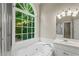 Bright bathroom featuring a soaking tub under a large window with views of the greenery outside at 1694 Peachcrest Ct, Lawrenceville, GA 30043