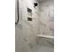 Walk-in shower featuring sleek marble tile and a built-in bench at 4814 Sultana Sw Way, Atlanta, GA 30331