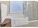 Bright bathroom featuring a glass block window, separate shower, and a soaking tub at 4845 Backbay St, Suwanee, GA 30024