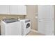 Well-equipped laundry room with white washer and dryer, storage cabinets, and tiled floor at 4845 Backbay St, Suwanee, GA 30024