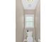 Neutral powder room with a toilet, toilet paper holder, and a small window at 4845 Backbay St, Suwanee, GA 30024