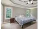 Comfortable bedroom with a tray ceiling, large windows, and a bed with stylish blue patterned covers at 2482 Windchase Dr, Buford, GA 30518