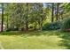 Lush backyard with mature trees, a manicured lawn, and flowering bushes provides a serene outdoor setting at 9041 Par Dr, Douglasville, GA 30134