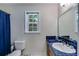 A modest bathroom shows a vanity with blue tile, a large mirror, and a window with a tree view at 9041 Par Dr, Douglasville, GA 30134