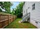 Side yard with wooden fence and steps to a white exterior door with green foliage in the background at 848 Fox Nw St, Atlanta, GA 30318