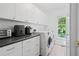 A spacious laundry room with white cabinets, a black countertop, and modern washer and dryer machines at 7635 Wynfield Dr, Cumming, GA 30040