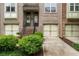Brick townhome with garages and covered stairway entrances, complemented by landscaping at 1973 Cobblestone Cir, Brookhaven, GA 30319