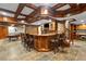 Finished basement bar area with stone backsplash, wooden bar with seating, and coffered ceiling at 4840 Spring Park Cir, Suwanee, GA 30024