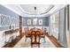 Formal dining room featuring elegant wainscoting, a tray ceiling, and natural light from a large window at 4840 Spring Park Cir, Suwanee, GA 30024