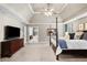 Large main bedroom featuring a four-poster bed, ceiling fan, and access to the ensuite bathroom at 4840 Spring Park Cir, Suwanee, GA 30024
